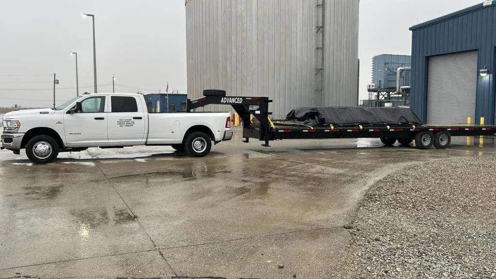 Red Shark Transport truck with tarped industrial load at night
